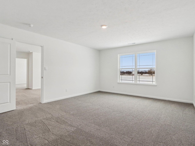 carpeted empty room featuring baseboards and a textured ceiling