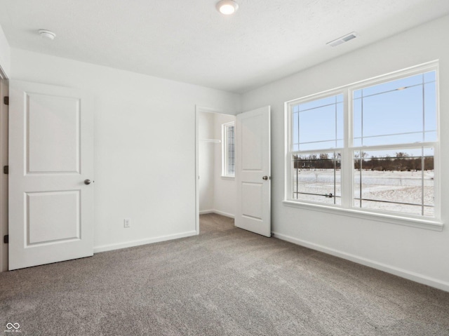 unfurnished bedroom featuring carpet floors, visible vents, and baseboards