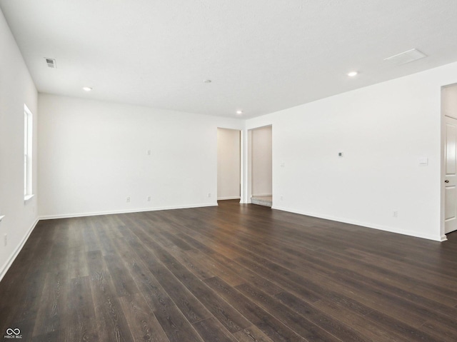 empty room featuring dark wood-style floors, recessed lighting, visible vents, and baseboards