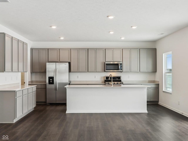 kitchen with a kitchen island with sink, stainless steel appliances, light countertops, and gray cabinetry