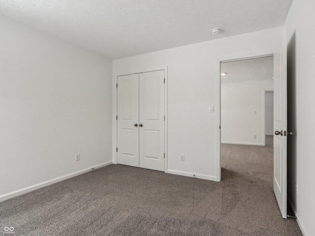 unfurnished bedroom featuring dark colored carpet, a closet, and baseboards