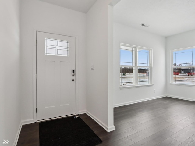 foyer with baseboards, visible vents, and dark wood-style flooring