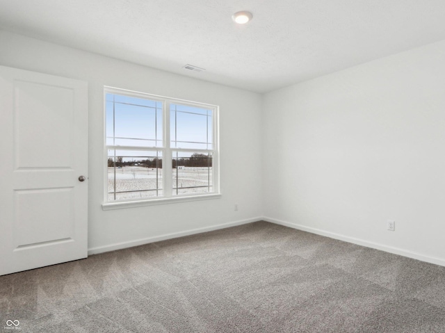 carpeted empty room featuring baseboards, visible vents, and a textured ceiling