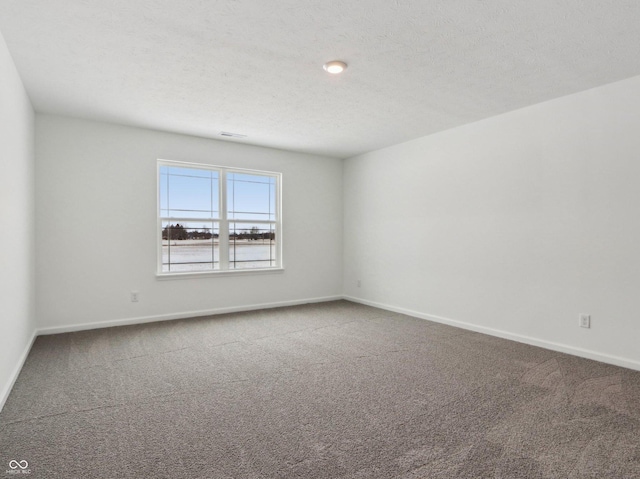 unfurnished room featuring a textured ceiling, carpet, and baseboards