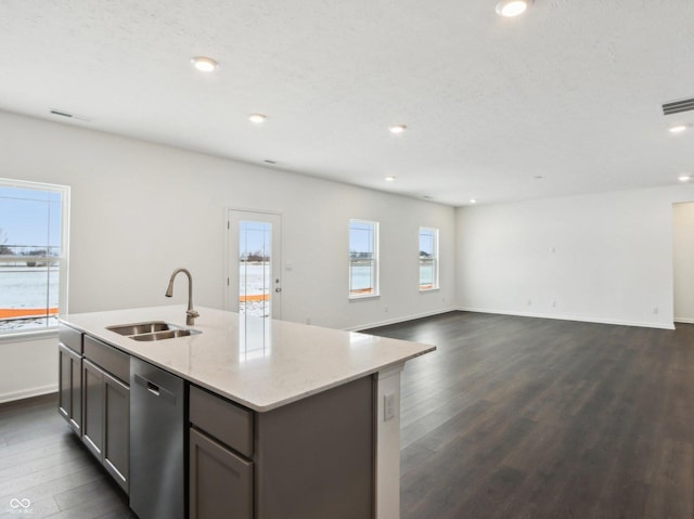 kitchen featuring visible vents, dishwasher, light stone counters, dark wood-type flooring, and a sink