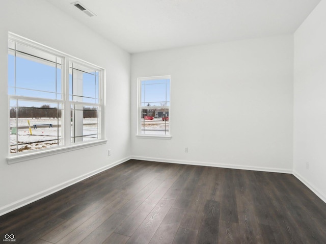 spare room featuring dark wood finished floors, visible vents, and baseboards