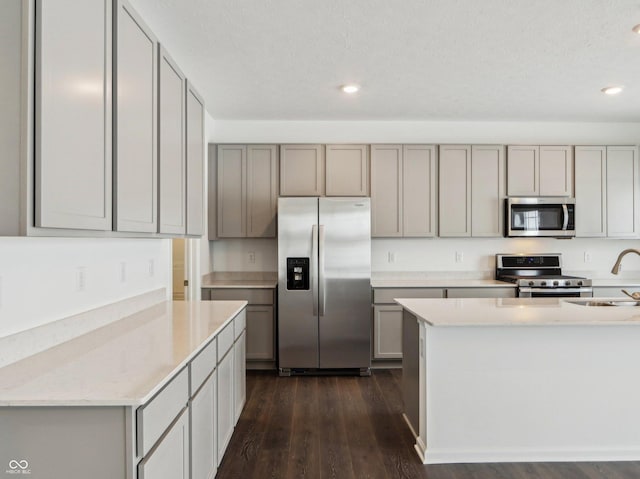 kitchen with recessed lighting, gray cabinetry, stainless steel appliances, dark wood-type flooring, and a sink