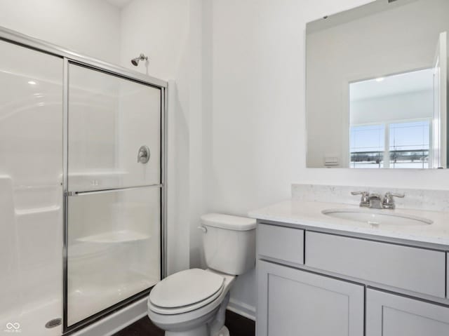 bathroom with toilet, a stall shower, and vanity