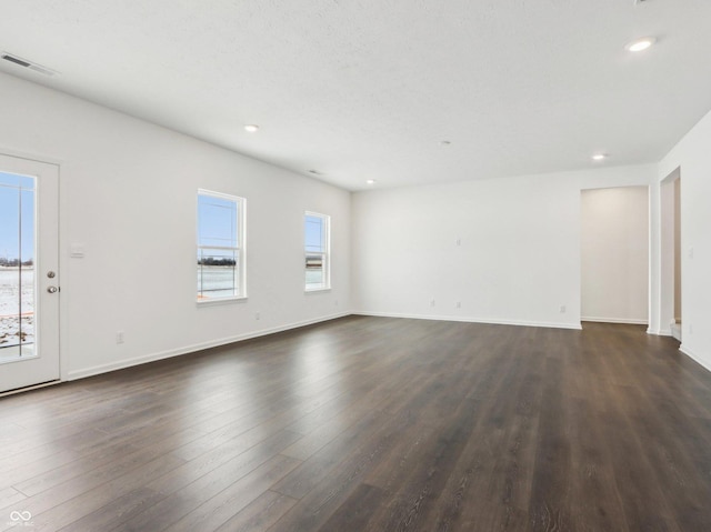 unfurnished living room with baseboards, visible vents, dark wood-style flooring, and recessed lighting