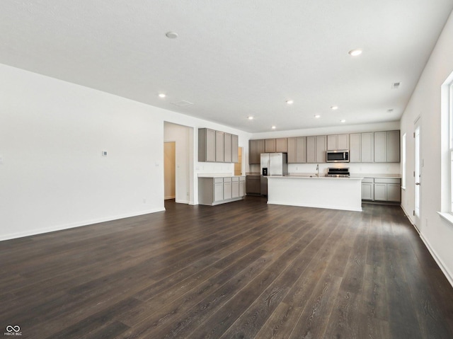 unfurnished living room with baseboards, dark wood-type flooring, a sink, and recessed lighting