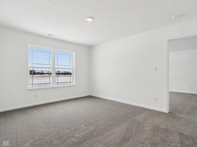 carpeted spare room featuring visible vents, baseboards, and a textured ceiling