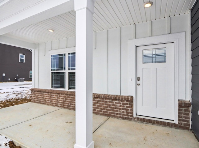 property entrance with board and batten siding and brick siding