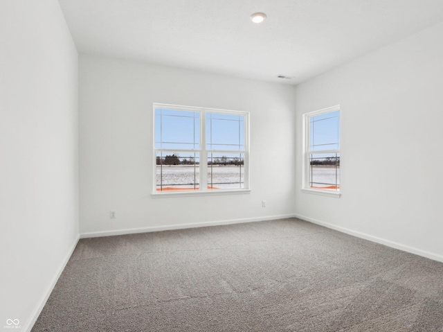 carpeted empty room featuring visible vents and baseboards