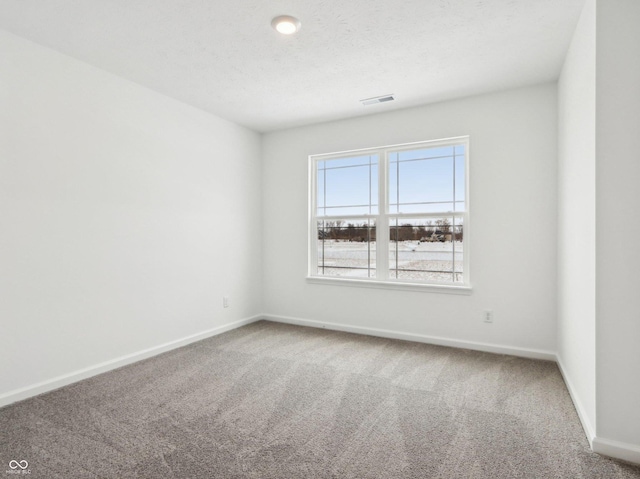 carpeted spare room featuring visible vents, a textured ceiling, and baseboards