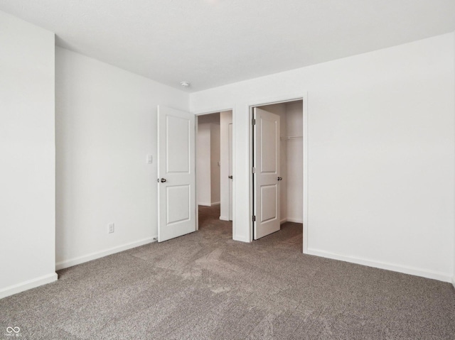 unfurnished bedroom featuring a spacious closet, carpet flooring, and baseboards