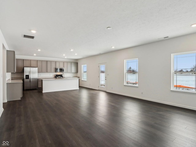 unfurnished living room with dark wood finished floors, recessed lighting, visible vents, a textured ceiling, and baseboards