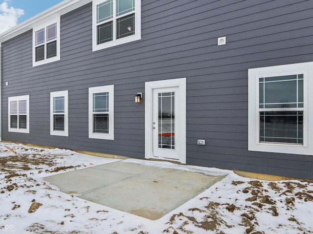 snow covered property entrance featuring a patio