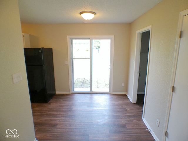 interior space featuring black fridge and dark hardwood / wood-style floors