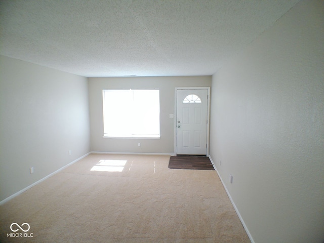 carpeted foyer entrance featuring a textured ceiling