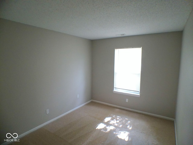 carpeted empty room with a textured ceiling