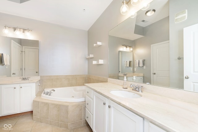 bathroom featuring vanity, tiled tub, and tile patterned flooring