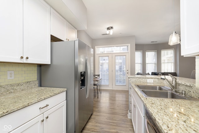 kitchen featuring sink, stainless steel fridge with ice dispenser, pendant lighting, white cabinets, and light hardwood / wood-style floors