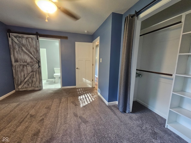 unfurnished bedroom with ceiling fan, a barn door, connected bathroom, and carpet