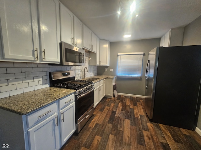 kitchen featuring dark wood-type flooring, dark stone countertops, sink, white cabinets, and appliances with stainless steel finishes