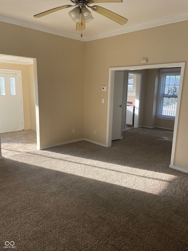 carpeted spare room featuring ceiling fan, crown molding, and washer / dryer