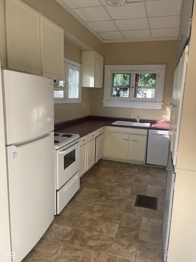 kitchen featuring a paneled ceiling, a wealth of natural light, white appliances, and sink