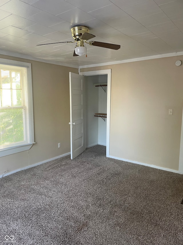 unfurnished bedroom with a closet, carpet, ornamental molding, and ceiling fan