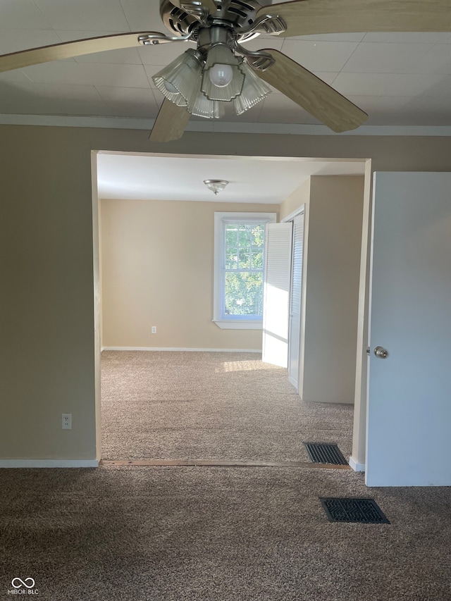 spare room featuring carpet floors, crown molding, and ceiling fan