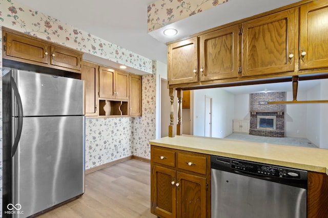 kitchen featuring kitchen peninsula, a fireplace, stainless steel appliances, and light hardwood / wood-style floors