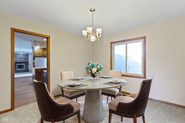 dining area featuring light carpet, a fireplace, and a notable chandelier