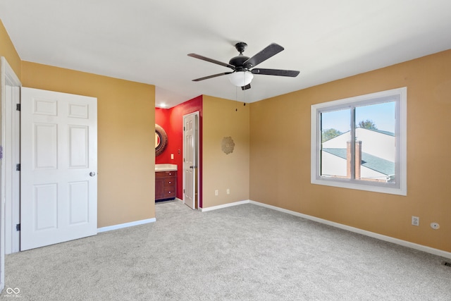 unfurnished bedroom featuring light carpet, ceiling fan, a closet, and connected bathroom