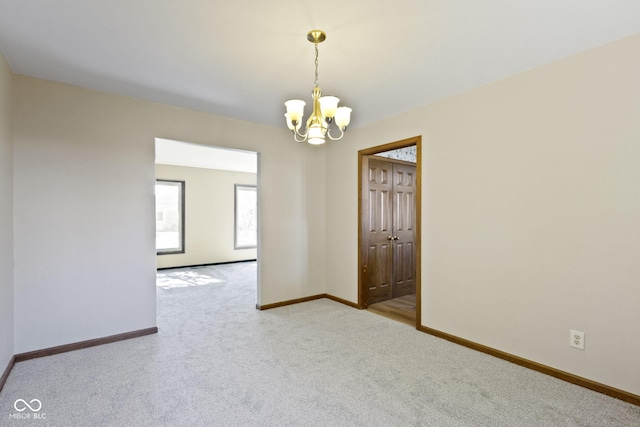 spare room featuring a chandelier and light colored carpet