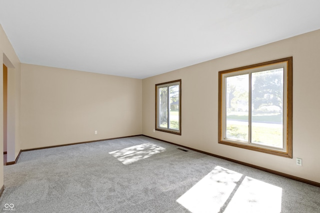 unfurnished room with light colored carpet and plenty of natural light