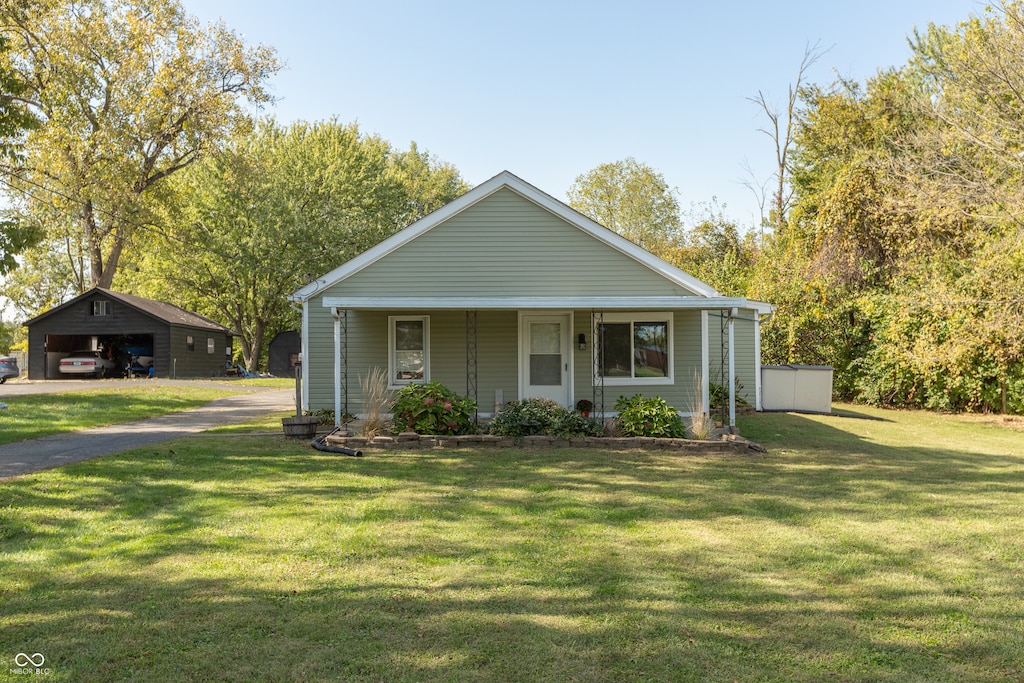 bungalow-style house featuring a porch, a storage shed, and a front lawn