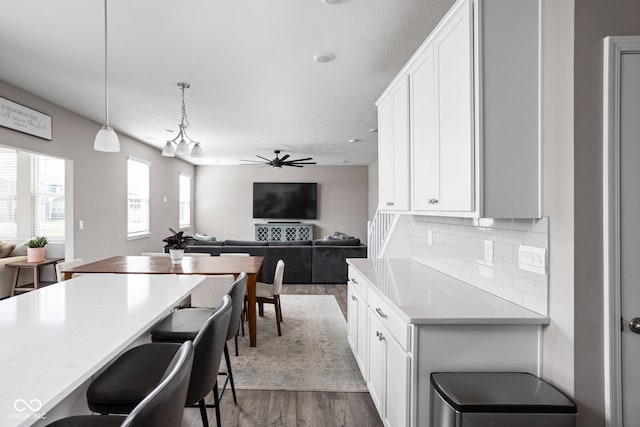 kitchen featuring white cabinets, light stone countertops, hanging light fixtures, and dark wood-type flooring