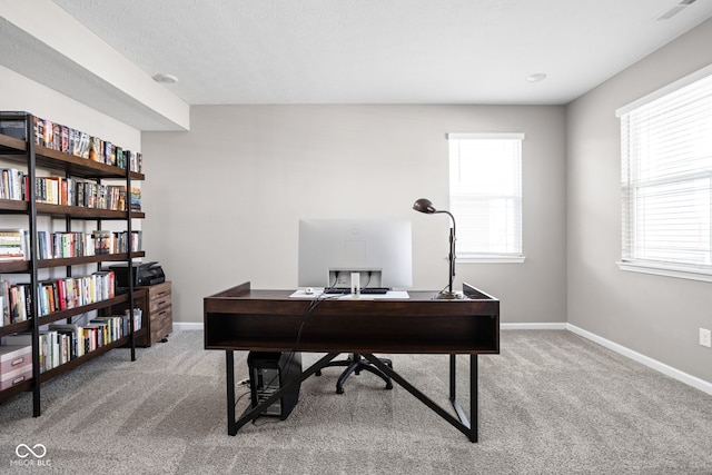 carpeted home office featuring a textured ceiling