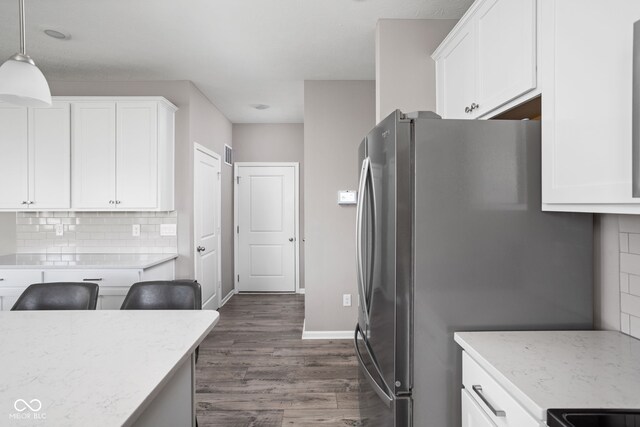 kitchen featuring stainless steel refrigerator, pendant lighting, tasteful backsplash, dark wood-type flooring, and white cabinets