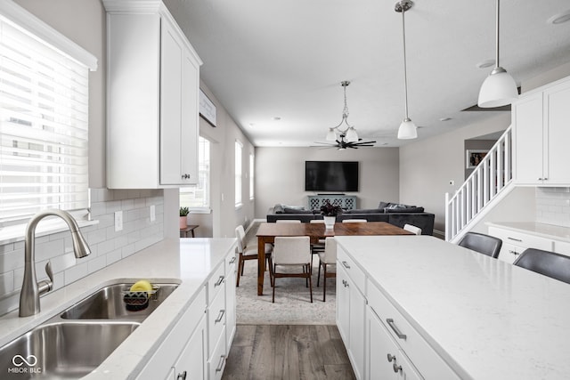 kitchen with hanging light fixtures, sink, dark wood-type flooring, white cabinetry, and decorative backsplash