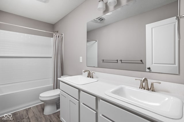 full bathroom featuring shower / tub combo, toilet, hardwood / wood-style flooring, vanity, and a textured ceiling