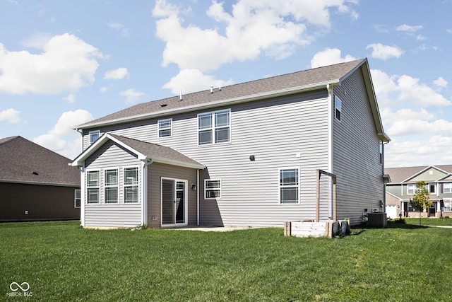 rear view of property with central air condition unit and a yard