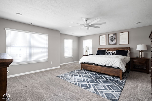 bedroom featuring dark colored carpet, ceiling fan, and a textured ceiling