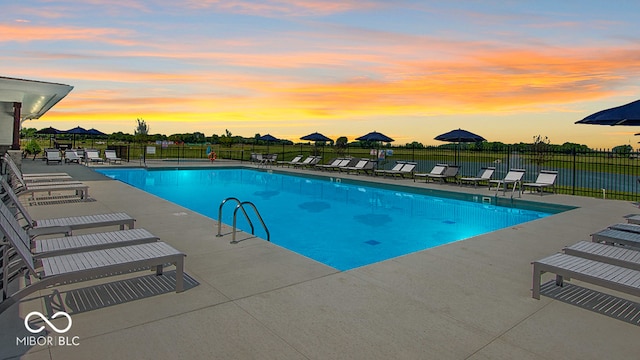 pool at dusk with a patio area