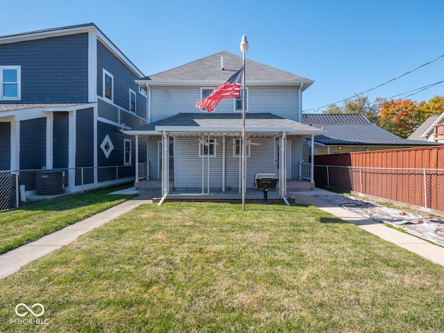 rear view of property featuring a lawn and a porch