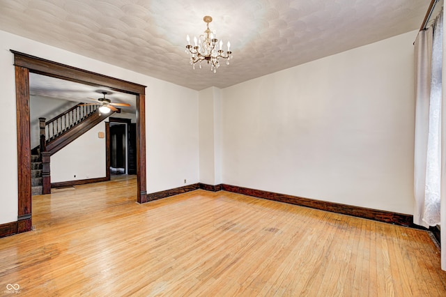 empty room featuring ceiling fan with notable chandelier, hardwood / wood-style floors, and a textured ceiling