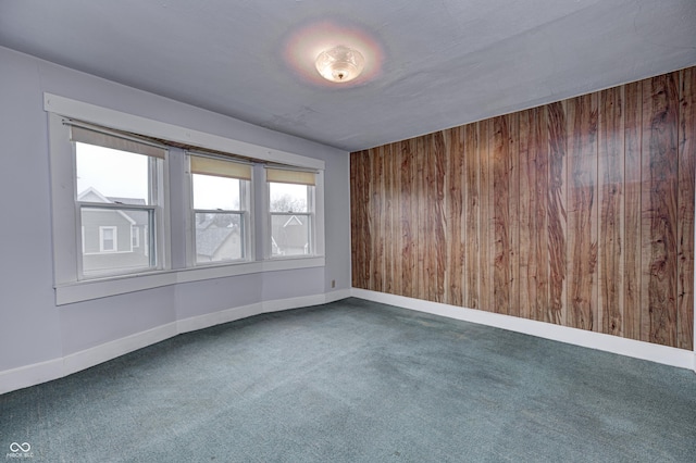 carpeted spare room with wooden walls