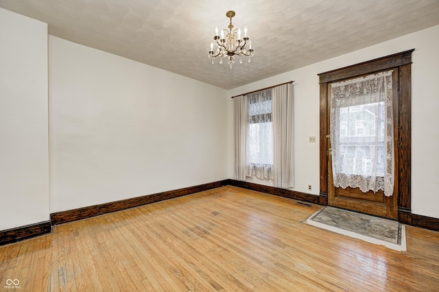 foyer entrance featuring hardwood / wood-style flooring, a textured ceiling, and a chandelier